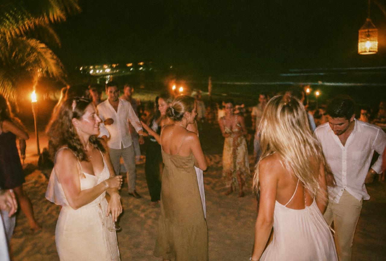 Guests dancing on the sand by torchlight at a beach club